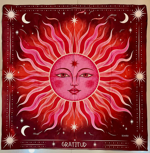 Pañoleta Gratitud en rojo y rosa con un sol de rostro ilustrado, lunas y estrellas en crema.